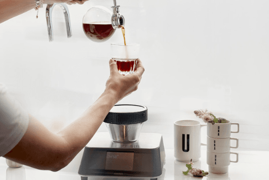 The photo shows the barista’s hands pouring coffee.